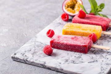 Assortment of fruit popsicles on a gray background