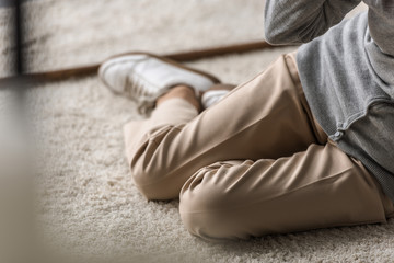 partial view of senior woman with heart attack sitting on carpet