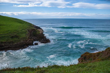 Sea inlet with rough blue sea on the green coast of Cantabria, Spain, Europe