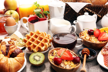 Huge healthy breakfast on table with coffee, orange juice, fruits, waffles and croissants. Good morning concept.