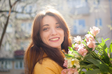 Female portrait of sensual brunette woman in yellow jacket holding a big bouquet of colorful...