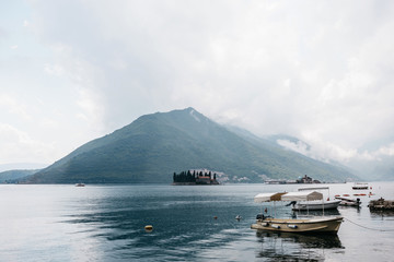 Beautiful view of the Bay of Kotor in Montenegro near the city of Perast. In the background there is an island with a church in the sea and in the foreground are many boats.