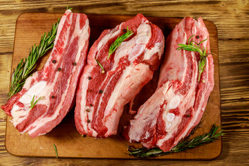 Raw pork ribs with spices and rosemary on wooden table. Top view
