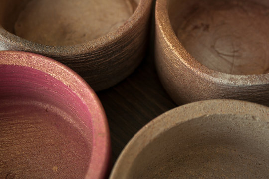 Four textured concrete pots spray painted in beige and pink colors with golden glitters close-up