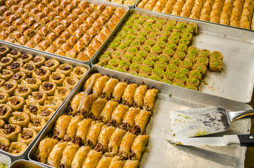 Traditional oriental dessert baklava. Middle Eastern sweetness on the street market. Turkish sweet baklava on a tray. Eastern sweets in a wide range. Arabic delight with almond, cashew pistachio 