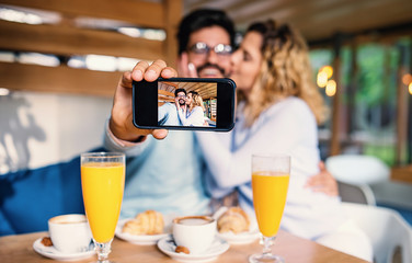 Beautiful young couple sitting in a cafe, having breakfast. Love, dating, food, lifestyle concept