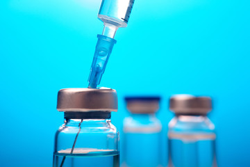 Vaccines and flu shot drug needle syringe on blue background
