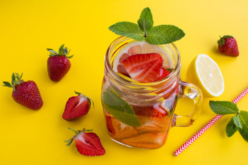 Detox or infused water with strawberry and lemon  in the glass  on the yellow background