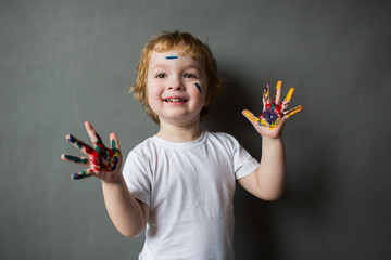little cute happy boy painted his fingers with paints, young artist