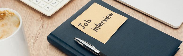 panoramic shot of notebook with job view lettering on sticky note on wooden surface with pen and cup of coffee