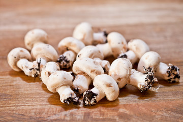 Fresh raw organic champignons heap on a wooden table.