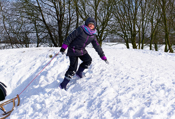Fototapeta na wymiar Mädchen rodelt im Schnee