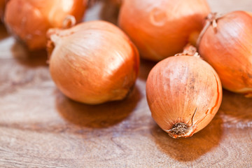 Fresh organic onions heap closeup on rustic wooden background.