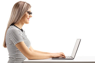 Young blond woman sitting and working on a laptop computer