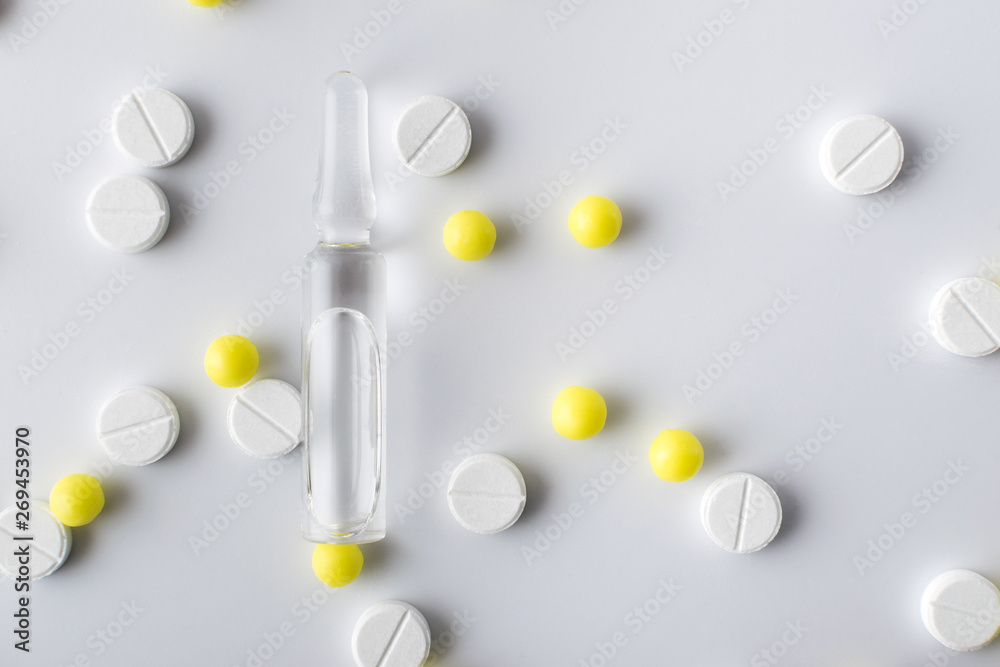 Poster medical ampoule next to white and yellow pills of medical drugs and vitamins are in the hospital on a white background