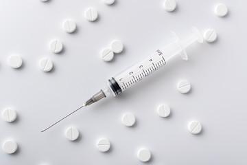 medical syringe next to the white pills of medicines and vitamins are in the hospital on a white background