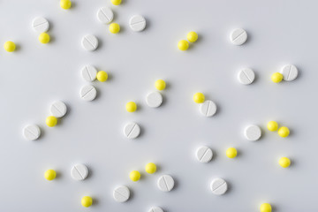 yellow and white pills of medical drugs and vitamins are in the hospital on a white background.