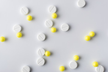 yellow and white pills of medical drugs and vitamins are in the hospital on a white background.