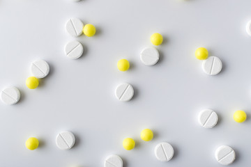 yellow and white pills of medical drugs and vitamins are in the hospital on a white background.