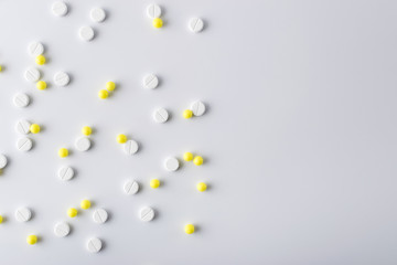 yellow and white pills of medical drugs and vitamins are in the hospital on a white background.