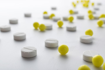 yellow and white pills of medical drugs and vitamins are in the hospital on a white background.