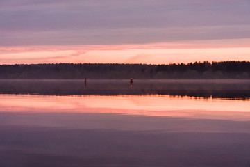 Fototapeta premium Buoy-enclosed fairway in the evening during a pink sunset