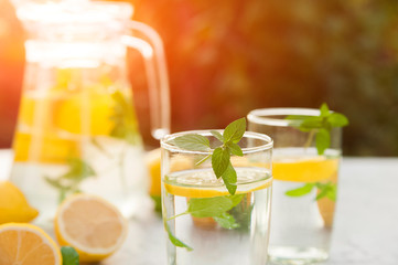 Homemade refreshing lemonade in decanter close-up and copy space. Lemonade from lemons, mint, ice.