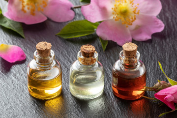 Obraz na płótnie Canvas Bottles of essential oil with dog rose flowers