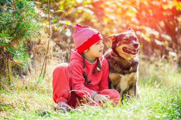 Fototapeta premium Happy little girl playing with dog in the forest