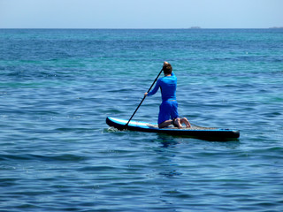 Fototapeta na wymiar young man practicing paddle on the beach with calm sea