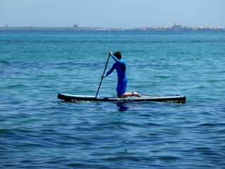 young man practicing paddle on the beach with calm sea
