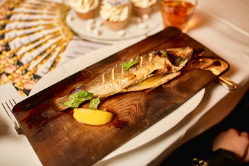 Grilled fresh trout served with lemon on wooden plate