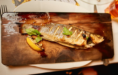 Grilled fresh trout served with lemon on wooden plate