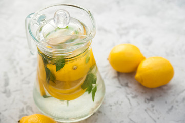 Homemade refreshing lemonade in decanter close-up and copy space. Lemonade from lemons, mint, ice.