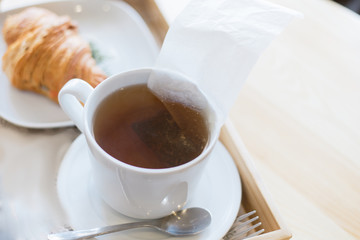 Tea with tea bag. Eco breakfast. Tea bag brewed in boiling water. Croissant for breakfast.