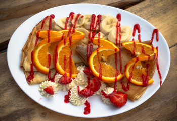 Pancakes with cranberry jam, strawberries, bananas, cream and strawberry topping.