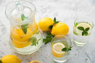 Homemade refreshing lemonade in decanter close-up and copy space. Lemonade from lemons, mint, ice.