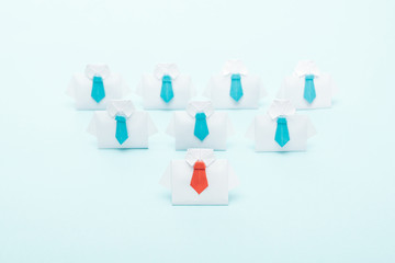 origami white shirts with blue ties with one red on blue background, leadership concept