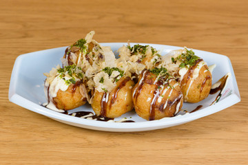 takoyaki, typical fried octopus meatballs, Osaka's culinary culture, garnished with cheese sauce, soy sauce and Katsuobushi, okaka, flakes of dried meat from skipjack tuna