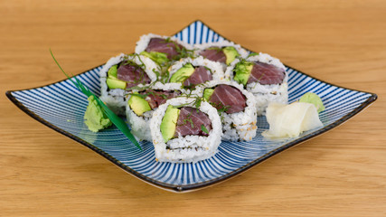 sushi roll of bluefin tuna, avocado, onion and rocket served on a decorated plate