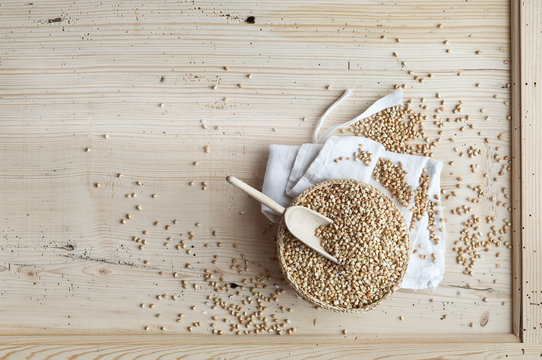 Organic buckwheat, whole grains in woven bowl on wood, from above
