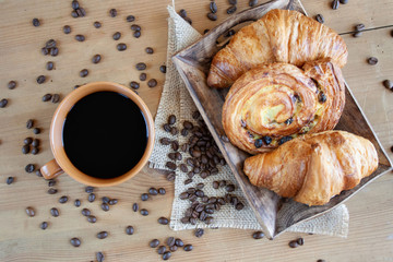 Sweet breakfast: black coffee, croissants and a roll with raisins