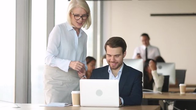 Friendly mature mentor coach executive help employee with computer work