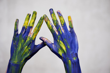 Hands in blue paint with yellow accents, hands of the artist and creative person. Yoga for hands