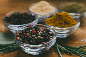 Variety of spices in round glass bowls - ground ginger, hops-suneli, kari, black pepper and mix