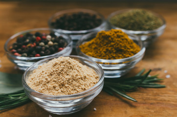 Round glass bowl with spice on a wooden table - ground ginger.