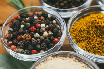 Variety of spices in round glass bowls - ground ginger, hops-suneli, kari, black pepper and mix