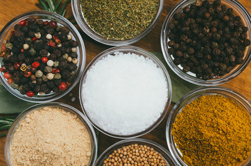 Variety of spices in round glass bowls - ground ginger, hops-suneli, kari, black pepper and mix