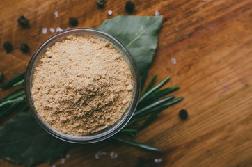 Round glass bowl with spice on a wooden table - ground ginger.