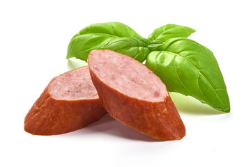 Sliced Bavarian Smoked Sausages with basil leaves, dry meat, close-up, isolated on white background